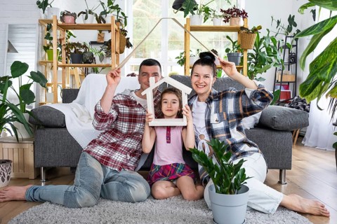 Traditional family with child are enjoying new home, sitting on the sofa and holding the roof.