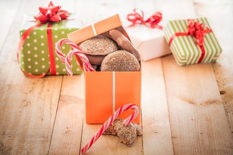 Orange colored gift box full of sweets, gingerbread and candies, on a wooden table