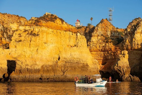 Stand-up paddler and fishing boat at Ponta de Piedade, Lagos, Algarve, Portugal, Europe