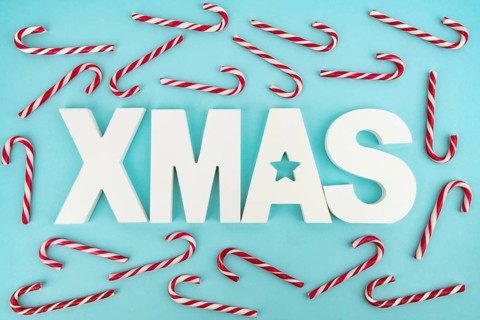 Zuckerstangen und hölzerne XMAS-Buchstaben auf blauem, hellem Hintergrund