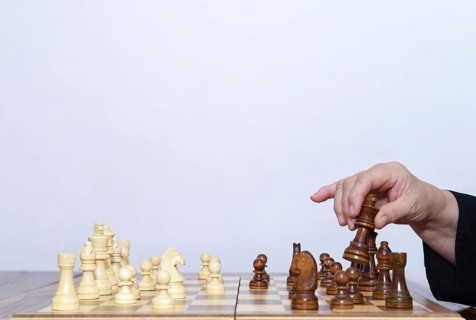 Close-up of a woman's hands playing chess with a white background and copy space