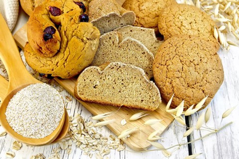 Bread, rolls and biscuits oat, bran in a spoonful, oat stalks on a background of wooden boards