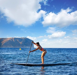 SUP Stand up Surf girl with paddle in a blue ocean sea