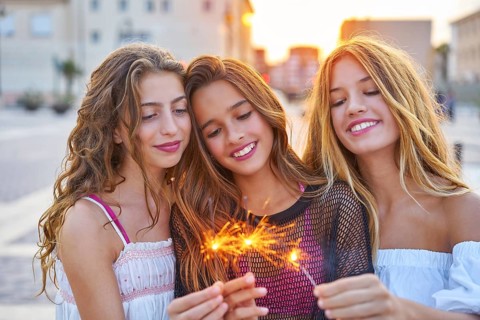 Best friends teen girls with sparklers at sunset in the city
