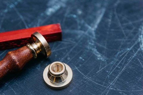 Brass seal with red wax on a textured dark background