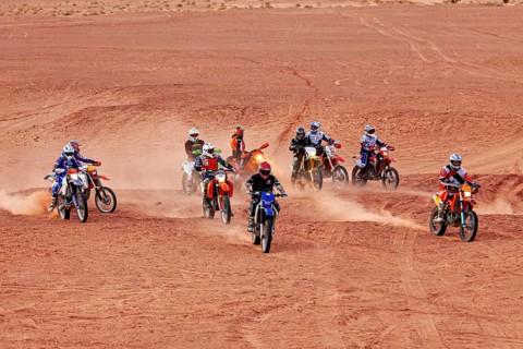 Several motorcyclists on the move, stirring up sand while driving in the desert, By off road