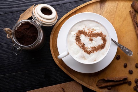 Porcelain cup of coffee with ice cream and cinnamon heart served at black wooden table. life style