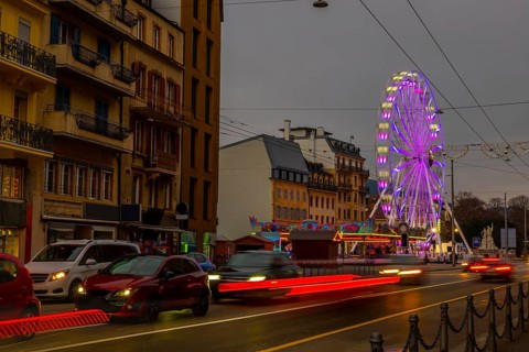 Traffic in Old Town with House and Building and Illuminated Ferris Wheel in a Cloudy Night in