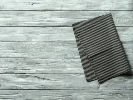 Gray wooden table with balck and white dark linen kitchen towel or textile napkin flat lay. Dark
