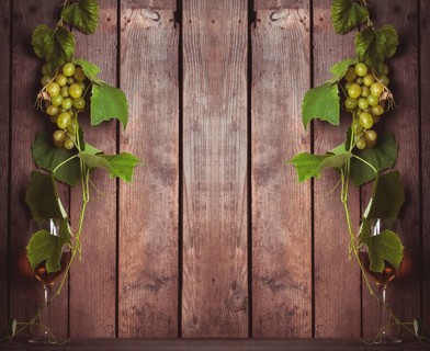 Grapes with leaves and glass of wine on the wood background