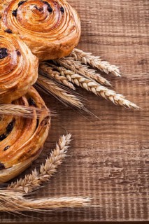 Ripe wheat ears rich rolls with raisins on oaken wooden board food and drink concept