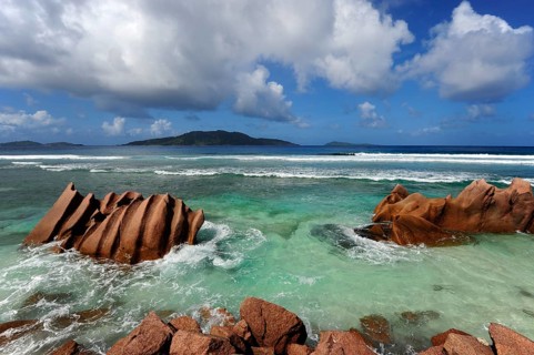 Rocks in the water at Anse Banane, with Felicite Island behind, La Digue Island, Seychelles, Indian