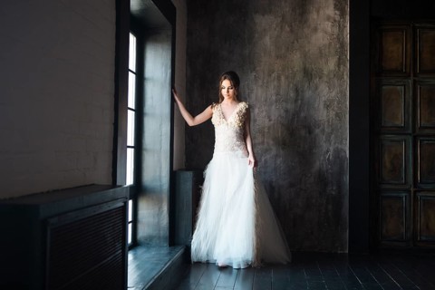 Portrait of beautiful young woman on dark background near the window