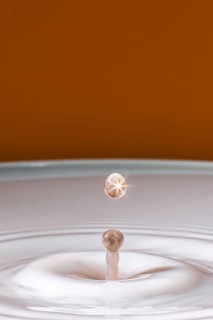 A sparkling drop hits the surface of the milk and creates gentle waves, water droplets, collision,