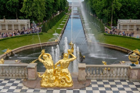 Magnificent garden fountain with golden sculptures and rising water jet, in the background