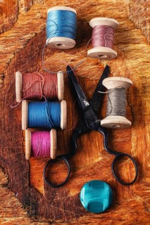 Six antiquated sewing threads and buttons on retro background