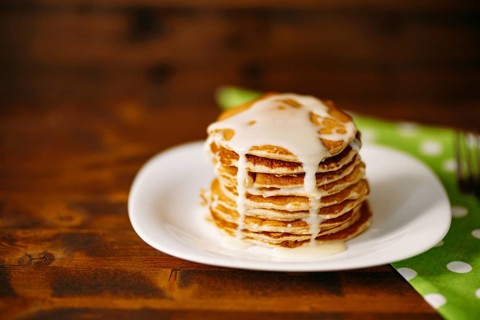 Condenced milk being poured on a stack of pancakes. High quality 4k footage