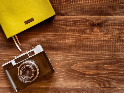 Top view vintage old camera and notebook on wooden background