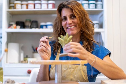 Artist smiling as she perfects her latest pottery piece