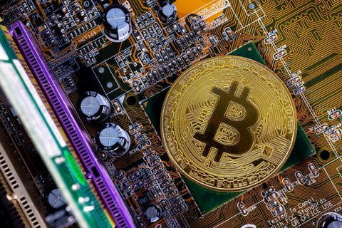 Virtual cryptocurrency money Bitcoin golden coin on a computer printed circuit board PCB. The