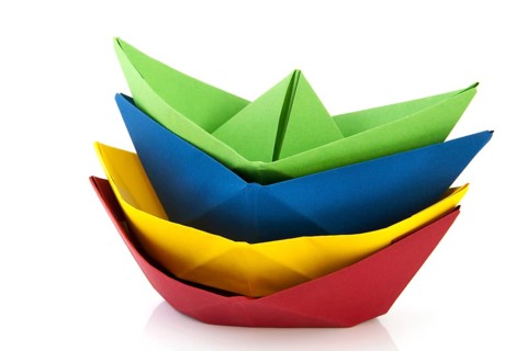 Stacked colorful folded paper boats isolated over white background