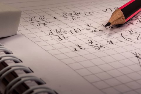 Pencil on notebook, full of mathematical formulas