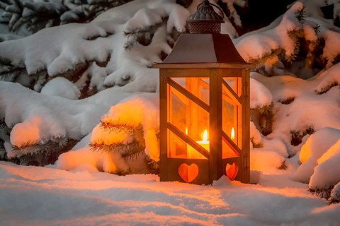 A lantern shines in the snow at Christmas. Romantic light on an evening in winter. Silence and
