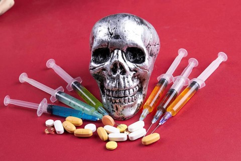 Composition of skull with syringes and pills on red background. Death from drug overdose concept