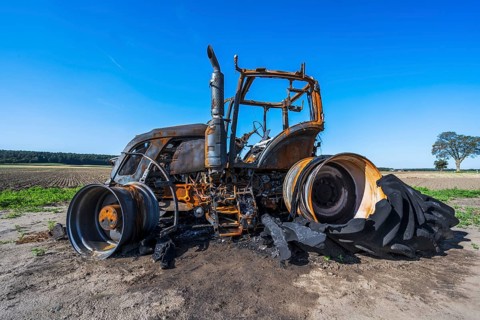 Fully destroyed burnt down tractor on a field