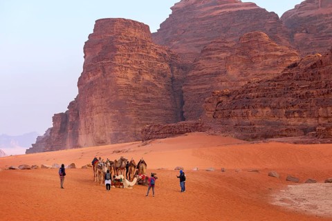 Jordan, Wadi Rum, November 2, 2022: Camels rest on the sand in the desert, people around. Sandstone