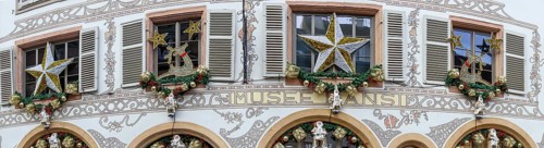 Panoramic photo of a shop front decorated for Christmas with many Father Christmases in golden