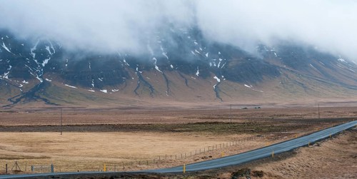 Rural empty straight road with mountains covered in fog at in Reykjanes peninsula in Iceland
