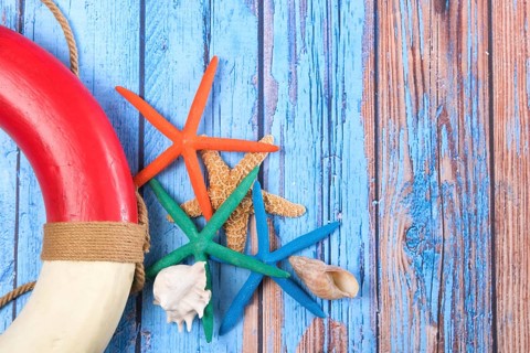 Beach poster on wooden background with starfishes and life buoy