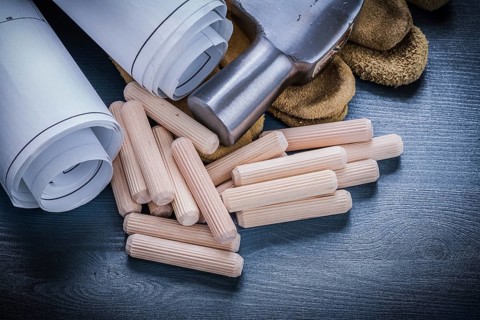 Close up view rolled blueprints hammer gloves wooden dowels