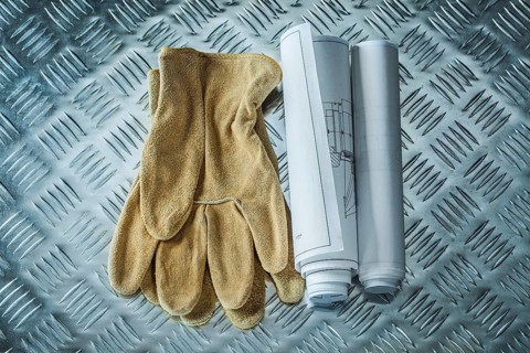 Construction drawings safety gloves on channeled metal sheet
