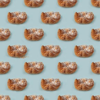 Puff pastry buns of fancy shape, with crumbs, on a blue background, pattern