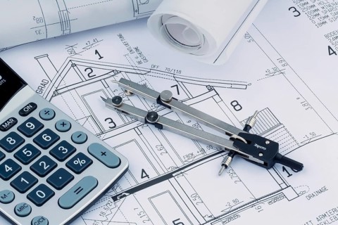 An architect's construction plan with a calculator. Symbolic photo for financing and planning a new