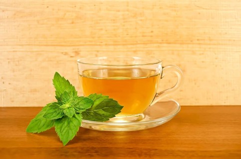 Herbal tea in a glass cup with mint on a background of wooden boards