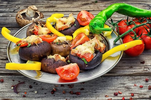 Easy appetiser of mushrooms stuffed with cheese, garlic and tomatoes.Rustic kitchen.Photo tinted