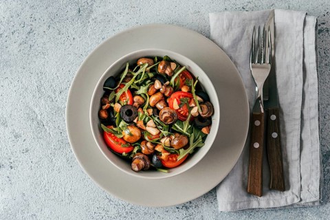Salad with arugula, mini champignons, cherry tomatoes, black olives, pine nuts. Vegetarian salad