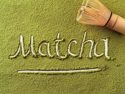 Matcha word over green matcha tea powder background and bamboo whisk Chasen. Top down view or flat