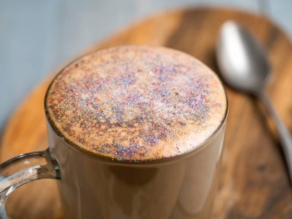 Trendy Coffee with edible glitter. Cup of sparkly coffee or diamond cappuccino on gray table. Copy