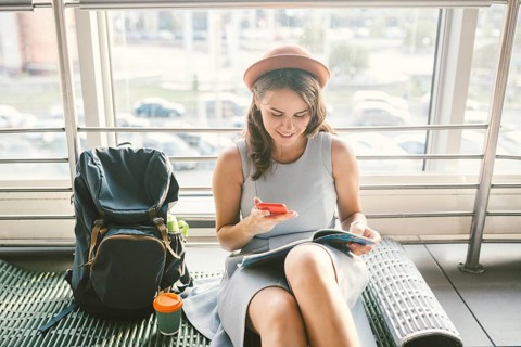 Theme of tourism and travel of young student. Beautiful young caucasian girl in dress and hat sits