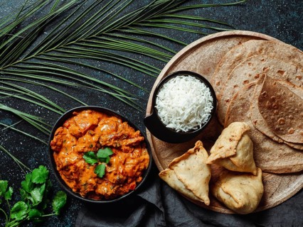 Indian cuisine dishes: tikka masala, rice, samosa, chapati, . Indian food on dark background with
