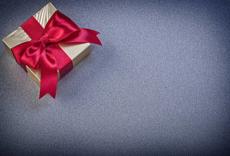 Present box with red knot on grey background holidays concept
