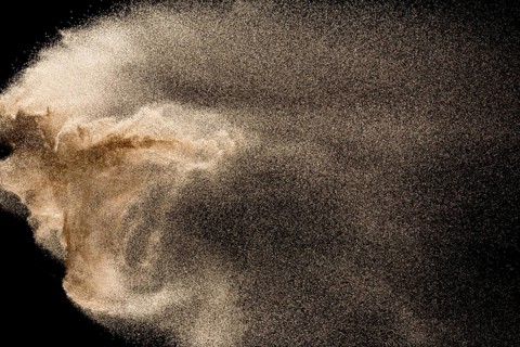 Dry river sand explosion. Golden colored sand splash against black background