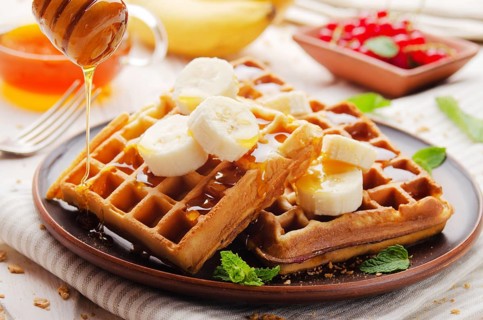 Homemade crispy Belgian waffles served with banana and honey