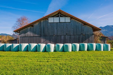 Barn with grass in round bales, round bale silage, on the Schweineberg, blue sky, near