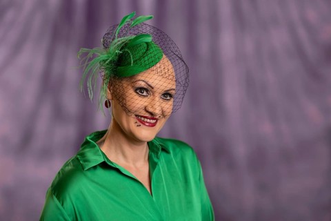 Woman smiling with green hat and net in front of purple background, Staged portrait shoot, Studio