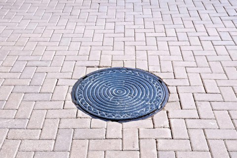 The road of brown tiles with a round metal hatch